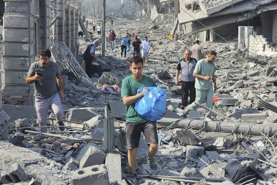 팔레스타인인들이 지난 10일 가자지구에서 이스라엘의 공습으로 파괴된 건물 잔해 속을 걷고 있다.