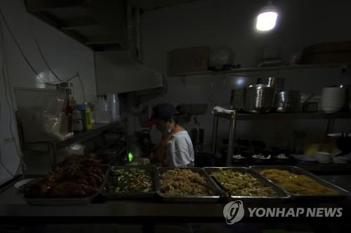 중국이 전력난이 시달리는 가운데 9월 29일 중국 선양의 한 식당에서 종업원이 전등불 하나에 의지에 일하는 모습