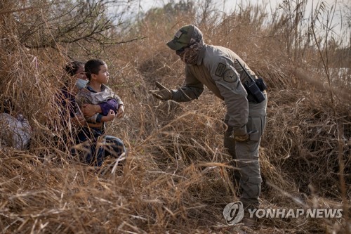 어린아이를 안고 밀입국하려다 텍사스주 경찰에 체포된 밀입국자 (사진 출처: 로이터 / 연합뉴스)