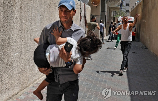 이스라엘군 공습에 아이 안고 대피하는 팔레스타인 남성 (가자시티 AFP=연합뉴스) 11일(현지시간) 팔레스타인 가자지구의 중심도시 가자시티에서 이스라엘군의 공습으로 한 남성이 아이를 품에 안은 채 대피하고 있다. 이슬람의 3대 성지 알아크사 사원 내에서 벌어진 팔레스타인 시위대와 이스라엘 경찰의 충돌 이후 이스라엘군과 가자지구를 통치하는 무장 정파 하마스의 무력 충돌이 이틀째 이어지고 있다.