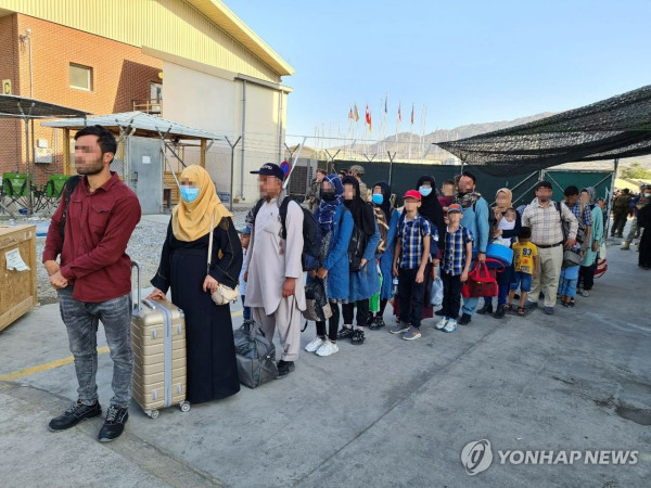 한국 정부와 협력한 아프가니스탄인들이 국내 이송을 위해 카불 공항에 도착한 한국 공군 수송기에 탑승하기 위해 줄을 서서 기다리고 있다.