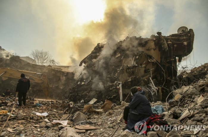 건물 잔해 옆에 서 있는 튀르키예 주민들 (사진 출처: 연합뉴스)