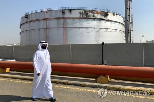 사우디 석유회사 아람코의 훼손된 석유저장고 앞을 지나는 마스크쓴 남성 [AFP=연합뉴스 자료사진]